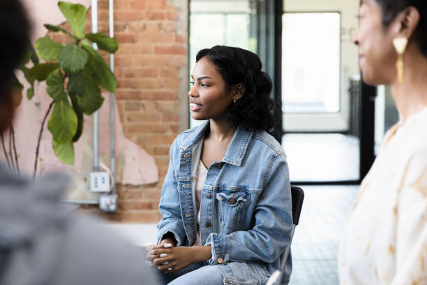 confident young woman listening attentively in a group therapy session.